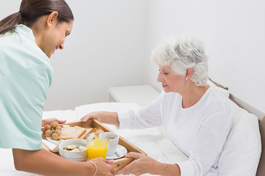 Elderly woman taking a breakfast with home nurse