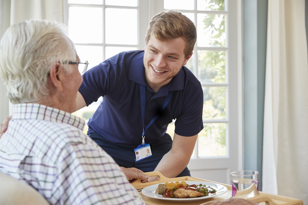 Male care worker serving dinner